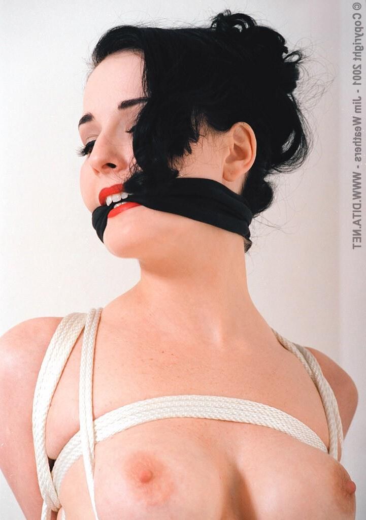 Dita von Teese gefesselt an einer Stange und über einer Bank